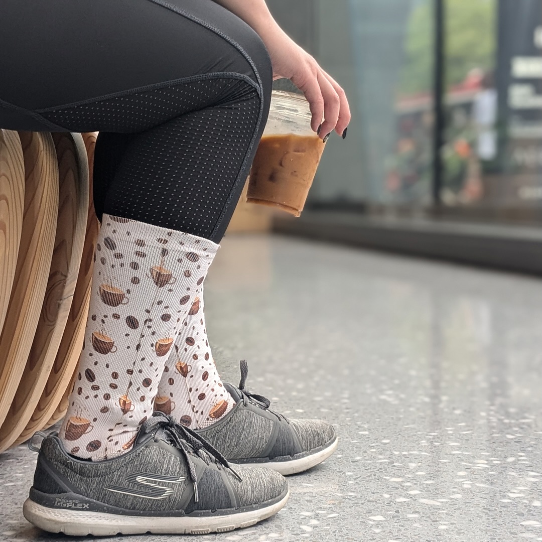  Low angle shot of someone holding coffee wearing her coffee designed socks