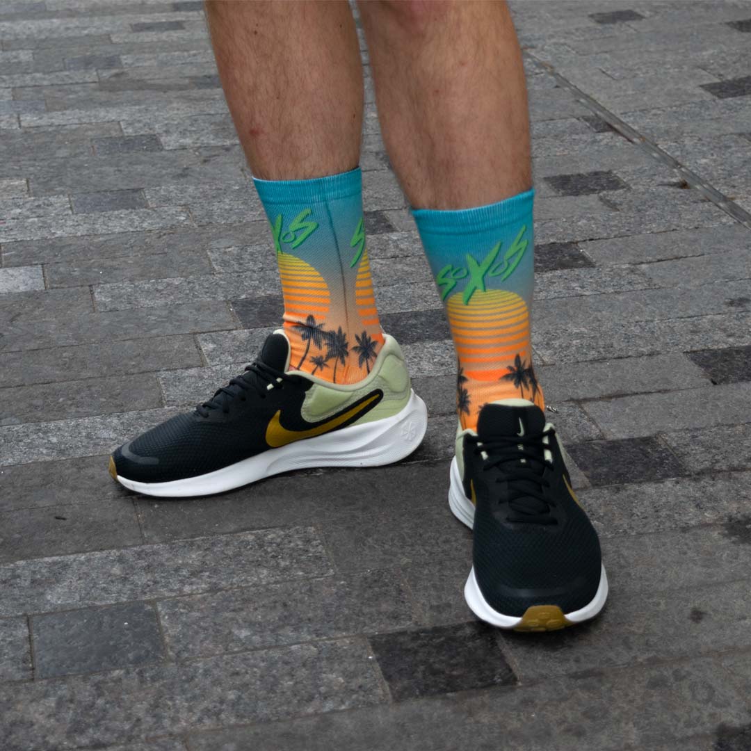 Person throwing a football upward while sitting down wearing custom socks