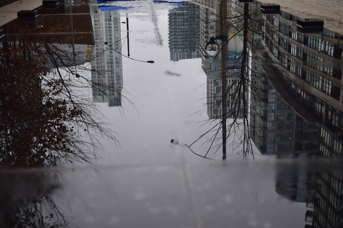 Large puddle with a reflection of the buildings above it